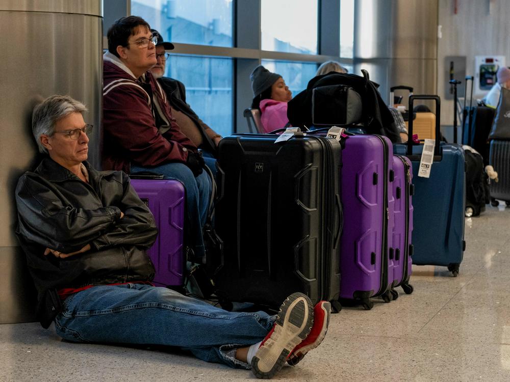 Travelers wait next to their luggage near the Southwest Airlines baggage claim area at the Nashville International Airport after the airline canceled thousands of flights in Nashville, Tenn., on Tuesday.