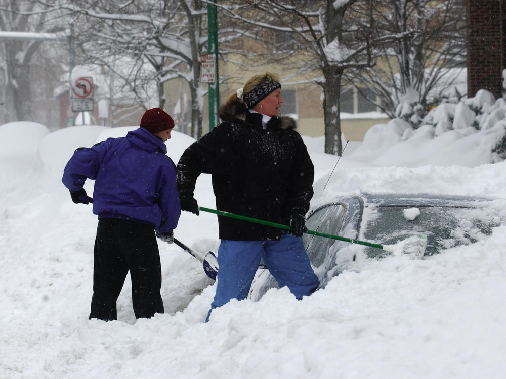 Laura Robinson (right) and Marty Dickinson of shovel out their car from a pile of snow on Wednesday in Buffalo, N.Y.