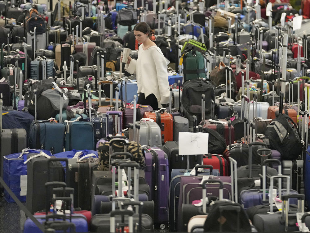 A woman walks through unclaimed bags at Southwest Airlines baggage claim at Salt Lake City International Airport on Thursday, as the carrier canceled another 2,350 flights after a winter storm overwhelmed its operations days ago.