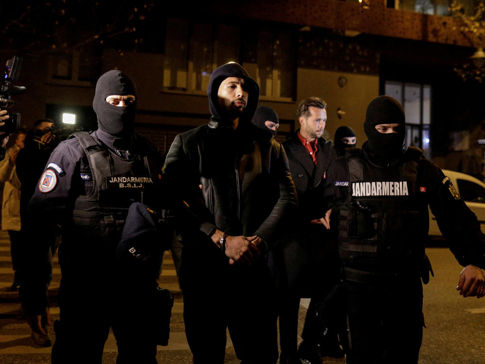Andrew Tate and Tristan Tate are escorted by police officers outside the headquarters of the Directorate for Investigating Organized Crime and Terrorism in Bucharest, Romania, on Thursday.