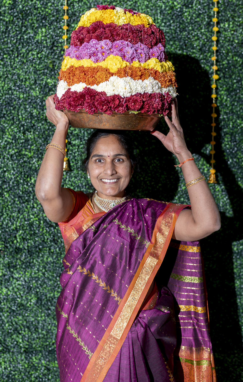 Anitha Kethireddy, 46, poses for a portrait in a saree as she carries the Bathukamma — a pyramid-shaped stack of flowers — on her head during a Bathukamma festival celebration organized by the Greater Lansing Telangana Community at the Okemos High School in Okemos, Mich., on Oct. 8, 2022.