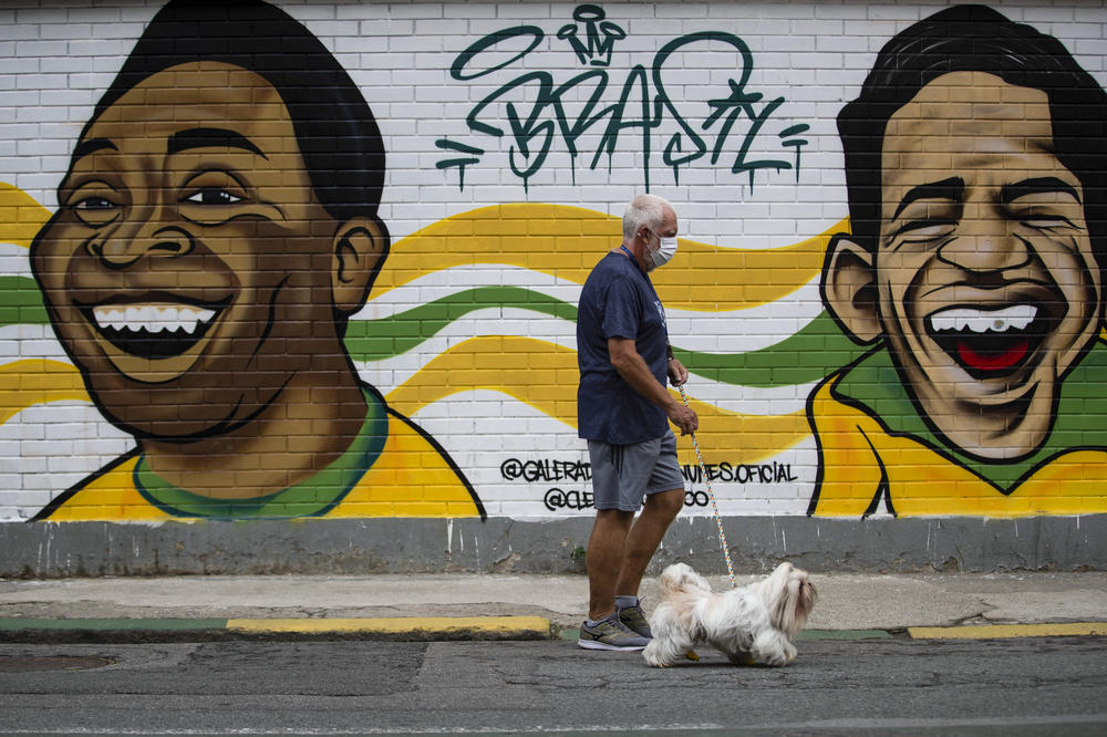 A man walks his dog past a mural of Brazilian soccer stars Pelé (left) and Garrincha in Rio de Janerio on Friday.