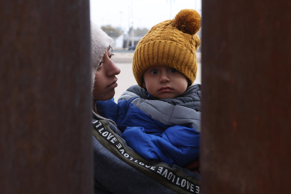 An asylum-seeking migrant from Ecuador holds her son on Wednesday as she waits at the border wall to be processed by U.S. Customs and Border Protection after crossing the Rio Grande in El Paso.