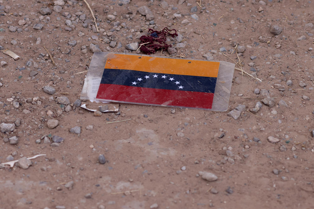 A Venezuelan flag is left by migrants near the border wall in El Paso on Thursday.