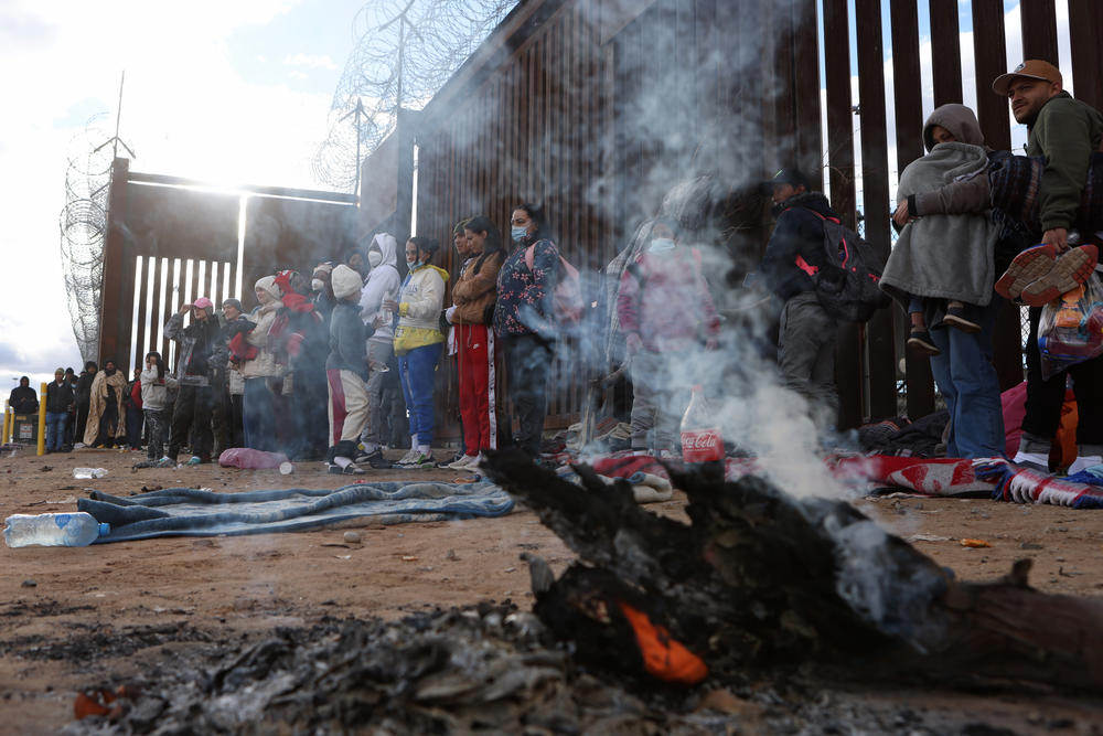 A fire smolders to keep asylum-seeking migrants warm as they wait to be escorted around the border wall to be processed by U.S. Customs and Border Protection after crossing the Rio Grande River into the United States in El Paso, Texas, U.S., Dec. 30, 2022.