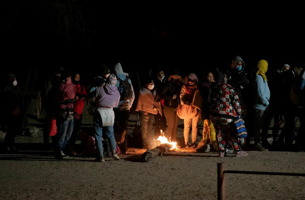 Asylum-seekers attempt to warm up next to a small fire as they wait to be processed by a U.S. Customs and Border Patrol agent near the U.S.-Mexico border fence near Somerton, Arizona.