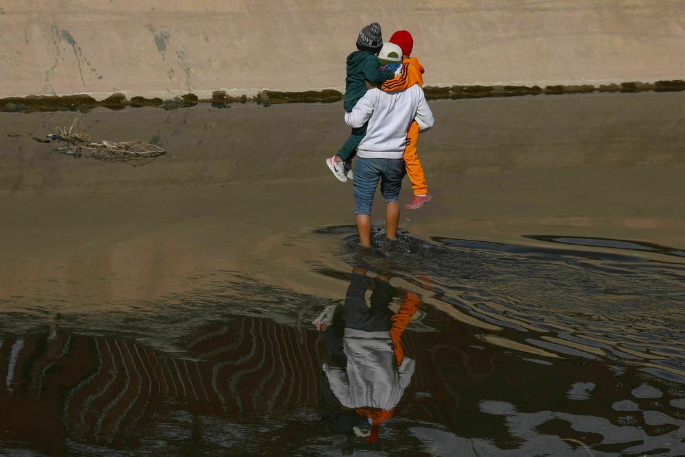 A migrant helps two Venezuelan children cross the Rio Grande river from Ciudad Juarez, Chihuahua state, Mexico to El Paso, Texas in search of political asylum.