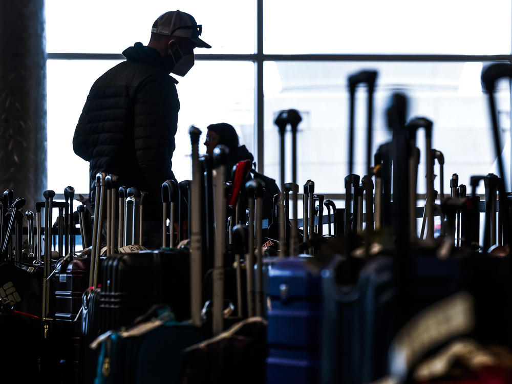 Travelers search for their suitcases in a baggage holding area for Southwest Airlines at Denver International Airport on Dec. 28 in Denver, Colo.