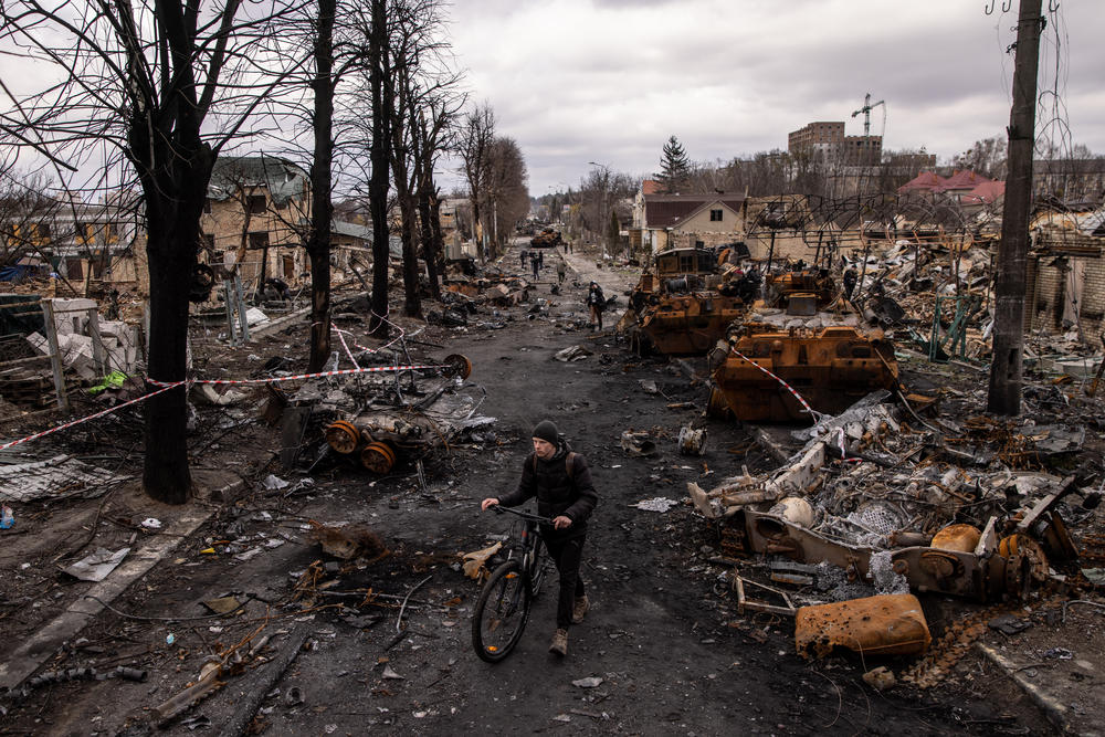A man pushes his bike through debris and destroyed Russian military vehicles in Bucha, Ukraine, on April 6. The Ukrainian government accused Russian forces of committing a 