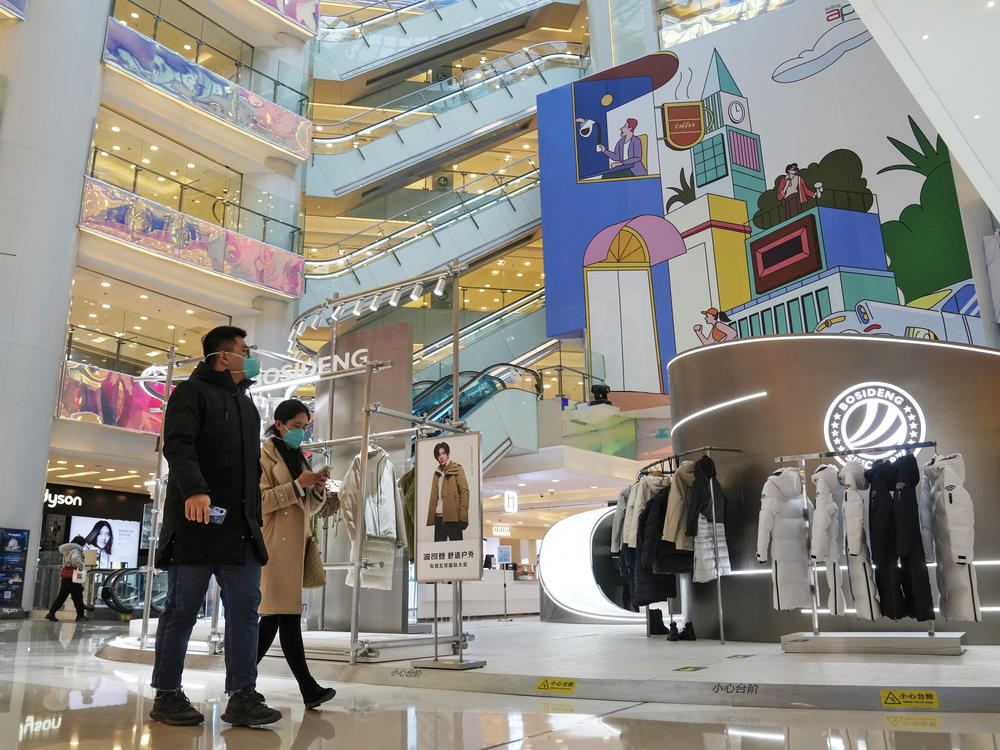 Shoppers walk through a reopened shopping mall after authorities started easing some of the anti-virus controls in Beijing on Dec. 6, 2022. Chinese manufacturing weakened for a third consecutive month in December, in the biggest drop since early 2020, as the country battles a nationwide COVID-19 surge after suddenly easing its anti-epidemic measures.