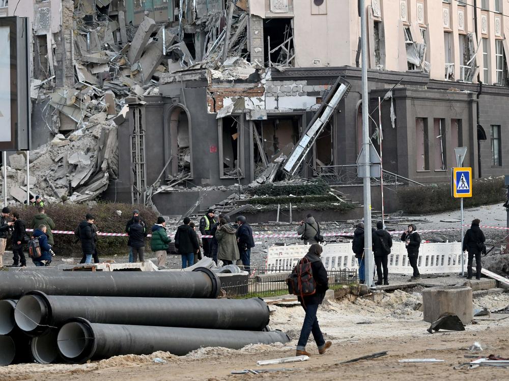People gather at the bottom of a hotel, which has been partially destroyed by a Russian strike in the center of the Ukrainian capital Kyiv on Saturday.