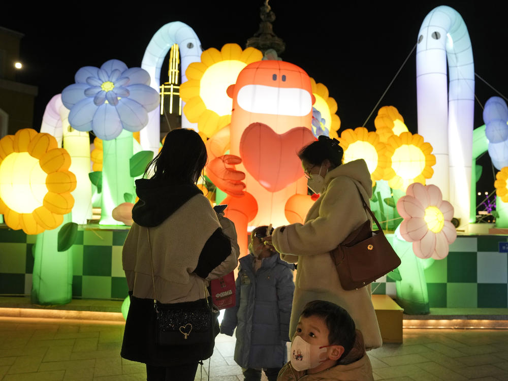 A child wearing a mask stands near light decorations at a mall in Beijing on Friday. China is on a bumpy road back to normal life as schools, shopping malls and restaurants fill up again following the abrupt end of some of the world's most severe restrictions even as hospitals are swamped with COVID-19 patients.