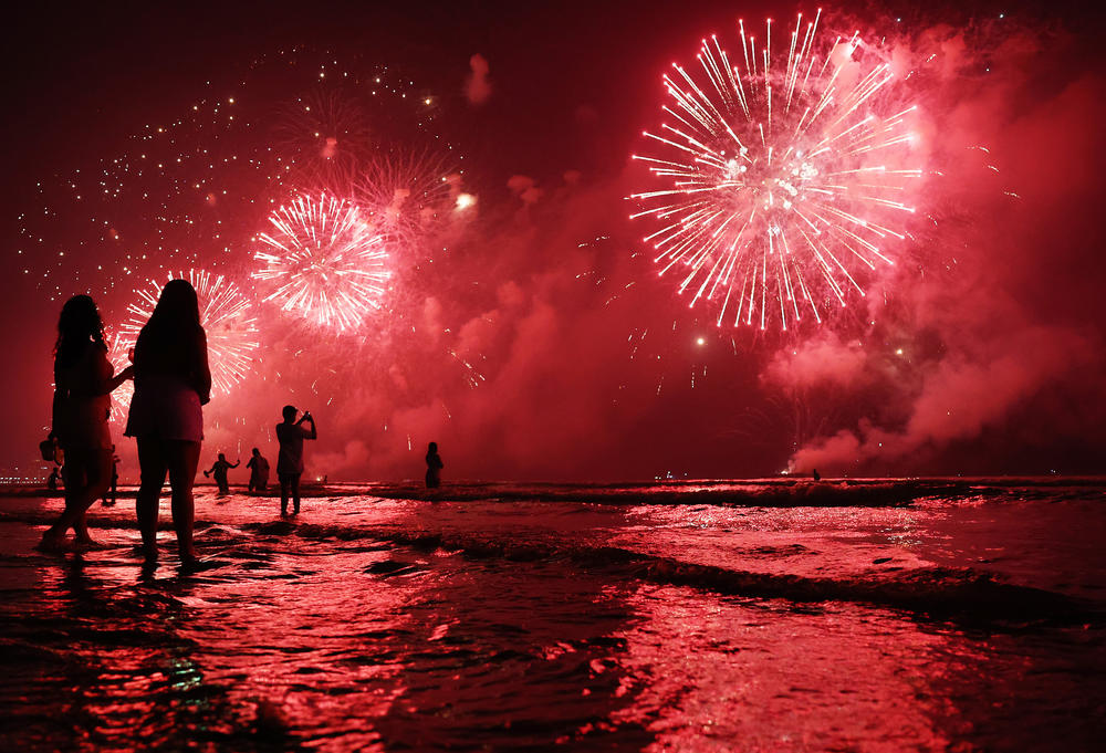 Brazilians celebrate during fireworks marking the start of the New Year at Gonzaga beach on Jan. 1, 2023 in Santos, Brazil.