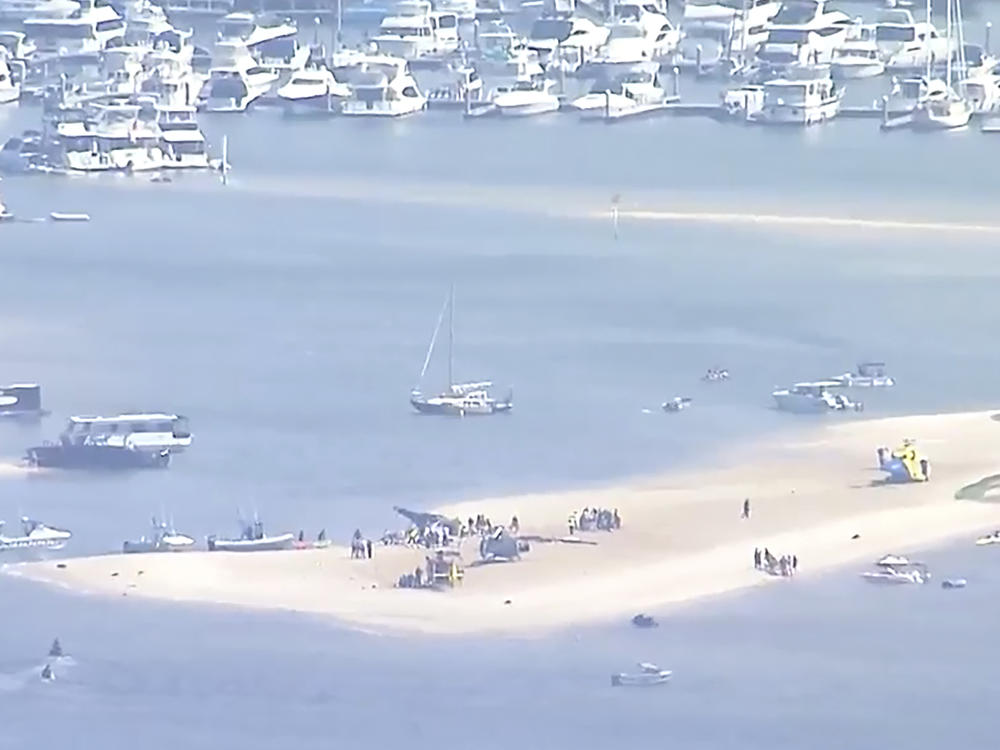 This image made from a video shows sand bank with crashed helicopter on Gold Coast, Australia Monday, Jan. 2, 2023. Two helicopters collided Monday afternoon over the Australian beach. (Australian Broadcasting Corp. via AP)