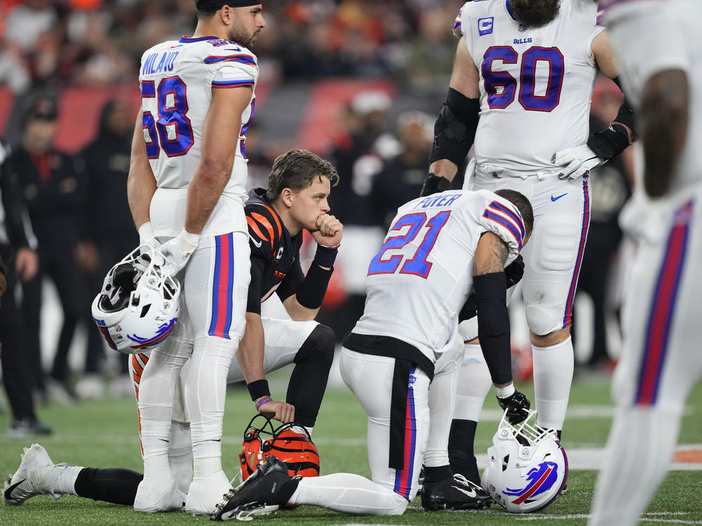 Quarterback Joe Burrow #9 of the Cincinnati Bengals and Jordan Poyer #21 of the Buffalo Bills take a knee after Damar Hamlin of the Bills collapsed during the the game on Monday.