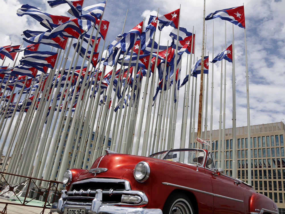 A classic American convertible car passes beside the United States embassy as Cuban flags fly at the Anti-Imperialist Tribune, a massive stage on the Malecon seaside promenade in Havana, Cuba, July 26, 2015.