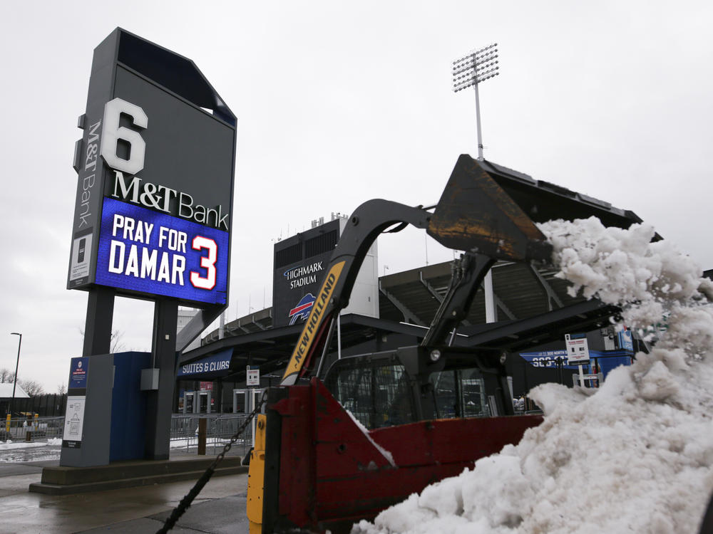 Crews clear snow from a parking lot near a sign showing support for Buffalo Bills safety Damar Hamlin outside Highmark Stadium on Wednesday in Orchard Park, N.Y.