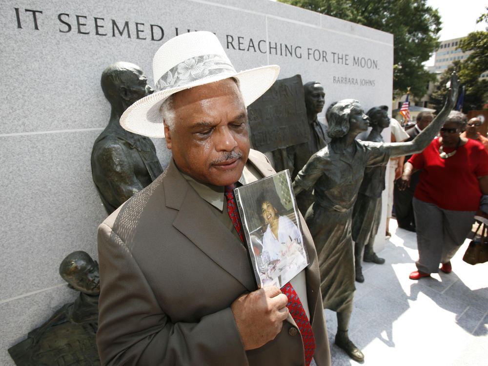 Roderick Johns holds a photo of his sister Barbara Johns at the newly dedicated Virginia Civil Rights Memorial on the grounds of the State Capitol in Richmond, Va. in July 2008.