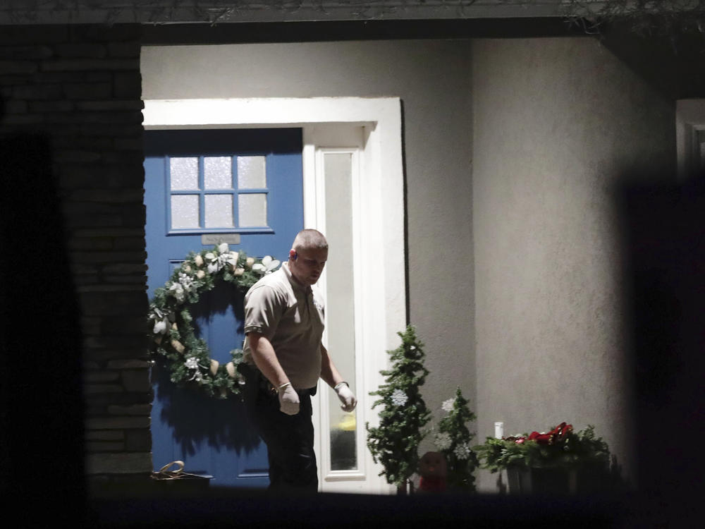 A law enforcement official stands near the front door of the Enoch, Utah, home where eight family members were found dead from gunshot wounds, Wednesday, Jan. 4, 2023.