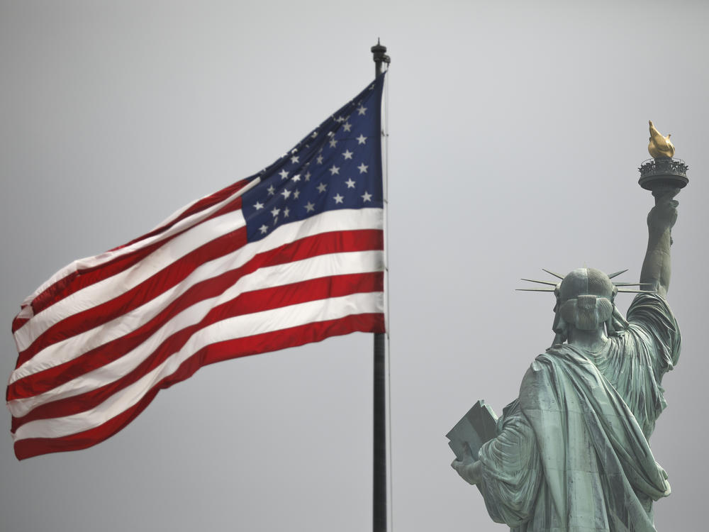 An America flag flies near the Statue of Liberty on Liberty Island.