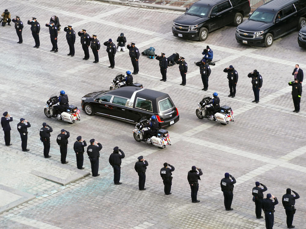 The hearse carrying the remains of Capitol Police officer Brian Sicknick drives past police officers saluting after a funeral ceremony at the US Capitol February 3, 2021 in Washington, DC.