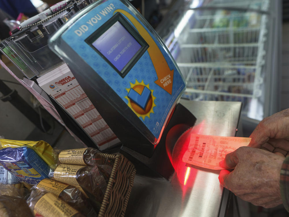 Roberto Ramirez checks his SuperLotto Plus ticket Friday at a gas station in Altadena, Calif.