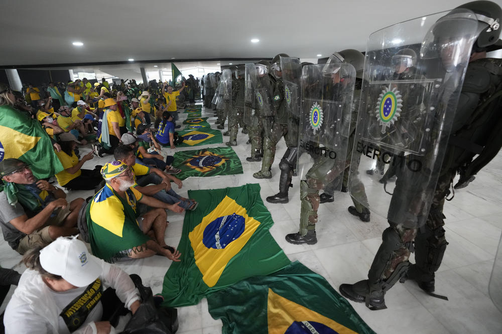 Supporters of Brazil's former President Jair Bolsonaro sit in front of police after inside Planalto Palace after storming it, in Brasilia, Brazil on Sunday. Planalto is the official workplace of the president of Brazil.