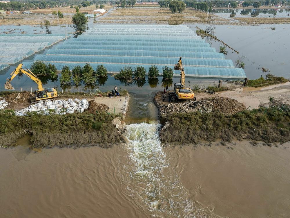 Rescuers dig a spillway to release flood waters after heavy rainfall in China's northern Shanxi province in 2021. A new report finds that human-caused climate change made the floods about twice as likely.