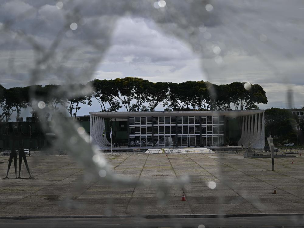 Brazil's Supreme Court building is seen through a broken window of the Planalto presidential building in Brasília on Monday, a day after supporters of Brazil's far-right ex-president, Jair Bolsonaro, invaded the Congress, presidential palace and Supreme Court.