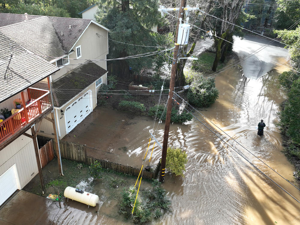 A resident walks through a flooded neighborhood Monday in Guerneville, Calif. The San Francisco Bay Area continues to get drenched by powerful atmospheric river events that have brought high winds and flooding rains.