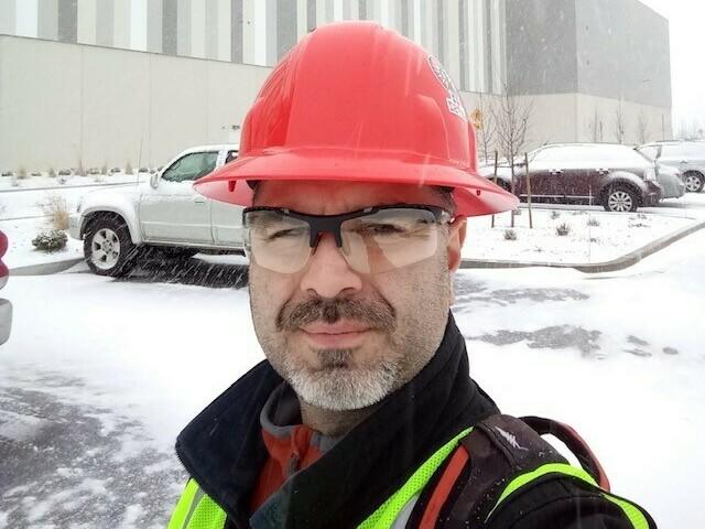 James Lopez stands in front of an Amazon building he helped construct in Washington state. Lopez has suspended a months-long housing search because his family can't afford to keep paying hundreds of dollars in rental application fees.