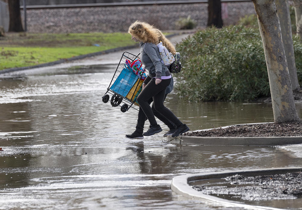 Residents in Merced, California wade across a flooded parking lot in the recent storms.
