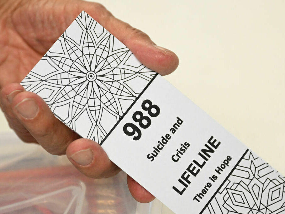A bookmark with the 988 Suicide and Crisis Lifeline is displayed by Lance Neiberger, a volunteer with the Natrona County Suicide Prevention Task Force, in Casper, Wyoming.