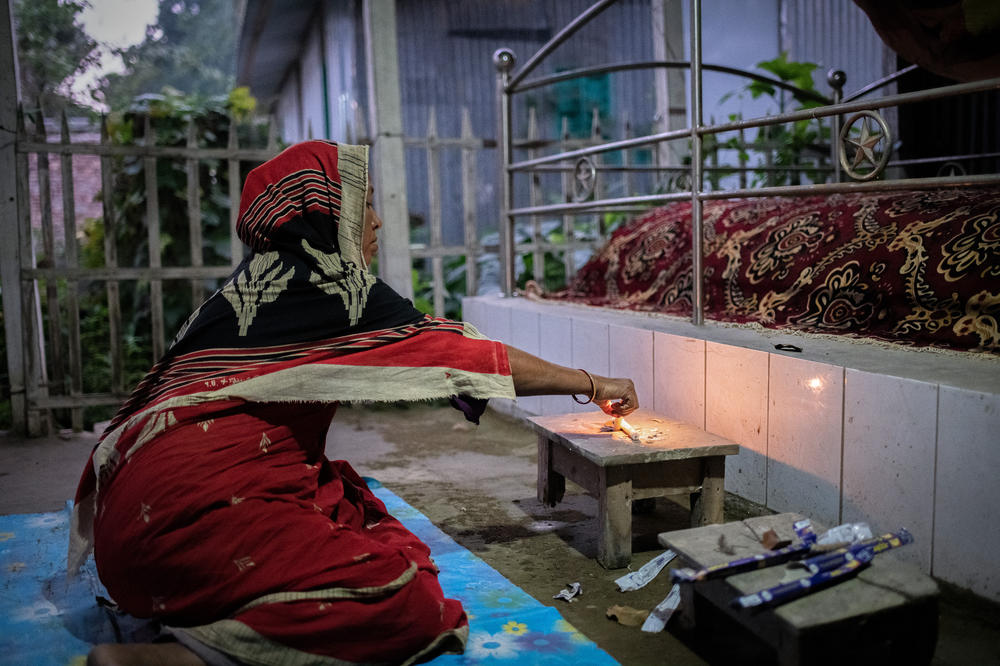 Anwara prays beside the grave of her father-in-law, a religious leader who died from Nipah virus in the 2004 outbreak in Faridpur, Bangladesh.