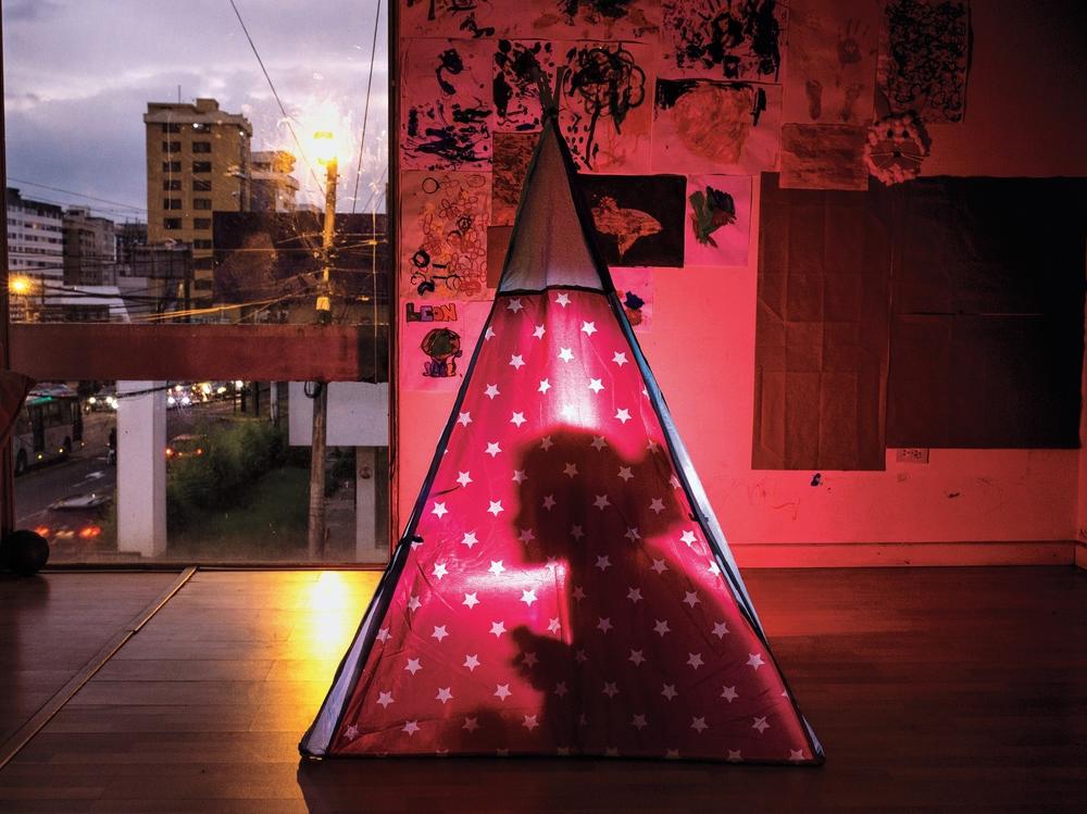 With the onset of the COVID-19 virus, 4-year-old Manuela Aguilar's education and school social life in Quito, Ecuador, changed dramatically. Here she plays with a flashlight, inside her camping tent, telling horror stories.