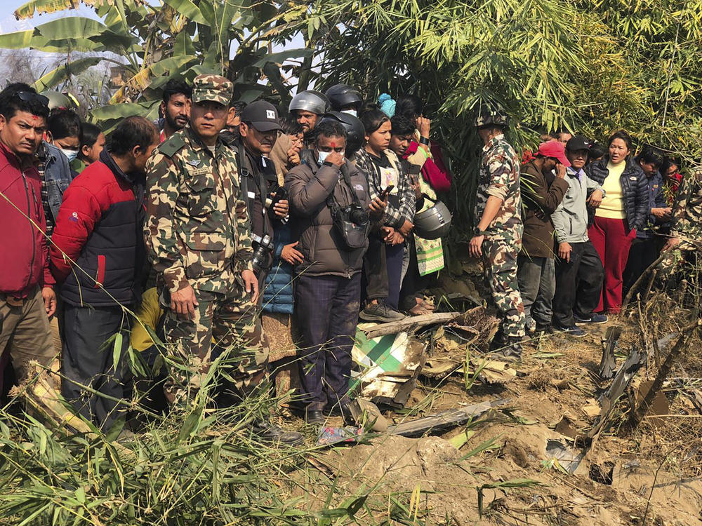 Locals watch the wreckage of a passenger plane in Pokhara, Nepal, Sunday, Jan.15, 2023. A passenger plane with 72 people on board has crashed near Pokhara International Airport in Nepal, the daily newspaper Kathmandu Post reports. The plane was carrying 68 passengers and four crew members.