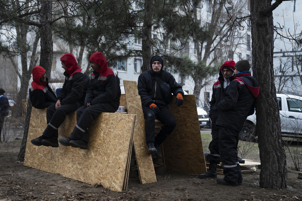 Municipal workers rest on some plywood during a break from fixing windows and clearing rubble.