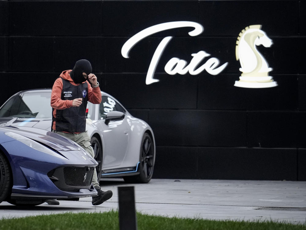 A police officer walks by luxury vehicles that were seized in a case against media influencer Andrew Tate, on the outskirts of Bucharest, Romania, on Saturday.