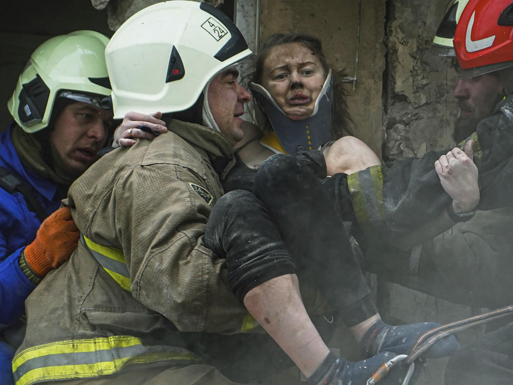 In this photo released by the State Emergency Service of Ukraine, firefighters carry a wounded woman out of the rubble of a building after a Russian rocket attack on Saturday in Dnipro.