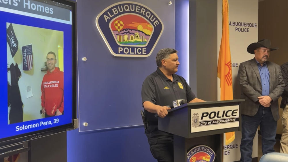 Albuquerque Police Chief Harold Medina speaks about the arrest of Solomon Peña, seen at left in an image projected onto a screen.
