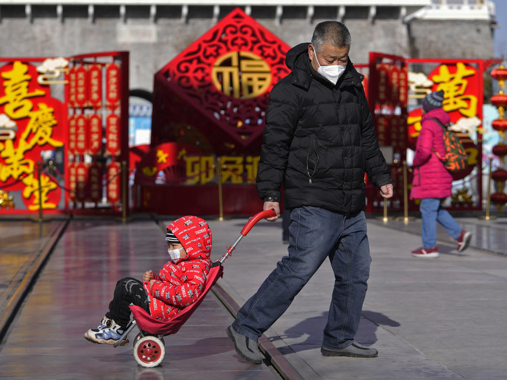 A man pulls a child past a Lunar New Year decoration on display at the Qianmen pedestrian shopping street, a popular tourist spot in Beijing, on Tuesday.