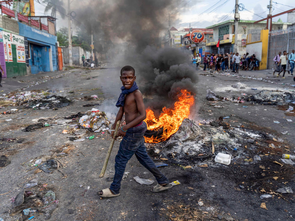 A man walks past a burning barricade during a protest against Haitian Prime Minister Ariel Henry, calling for his resignation, in Port-au-Prince.