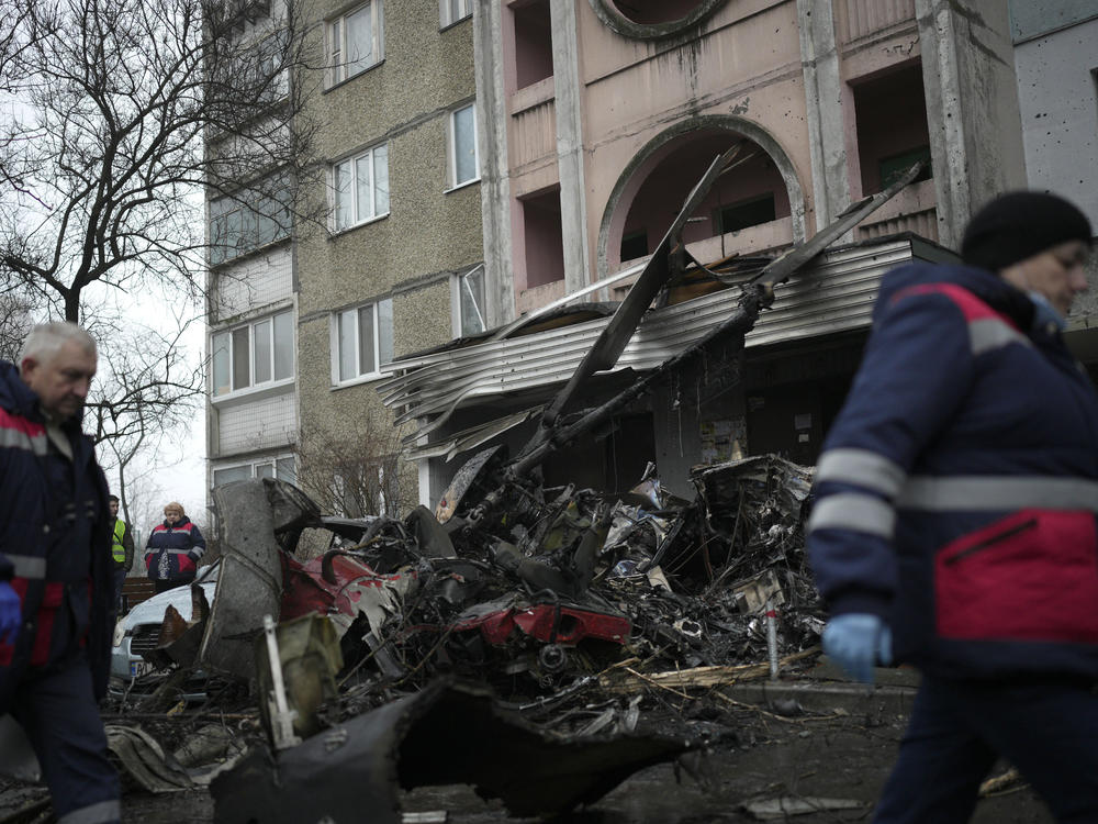 Workers pass the scene where a helicopter crashed in Brovary, on the outskirts of Kyiv, Ukraine, Wednesday. The chief of Ukraine's National Police says the crash in a Kyiv suburb has killed 18 people, including Ukraine's interior minister and two children.