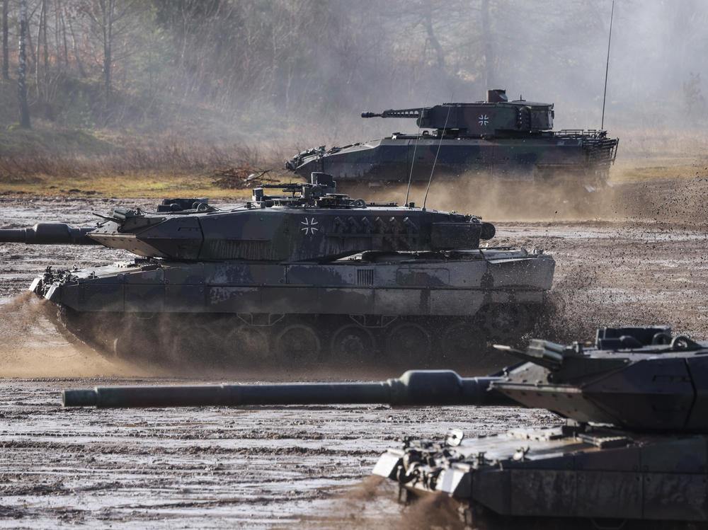 Two Leopard 2 A6 heavy battle tanks and a Puma infantry fighting vehicle of the Bundeswehr's 9th Panzer Training Brigade participate in a demonstration of capabilities during a visit by then-Defense Minister Christine Lambrecht to the Bundeswehr Army training grounds in February 2022 in Munster, Germany.