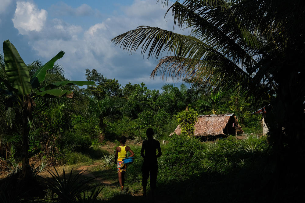 A young woman and man walk through Dologan's Town, Liberia, on Nov. 16, 2022.