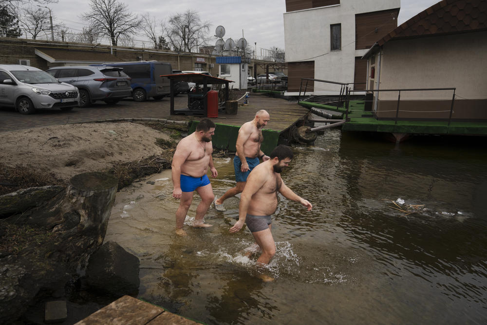 People gather in small groups to wade into the icy waters of the Dnipro River to mark the Christian holiday of Epiphany on Thursday.
