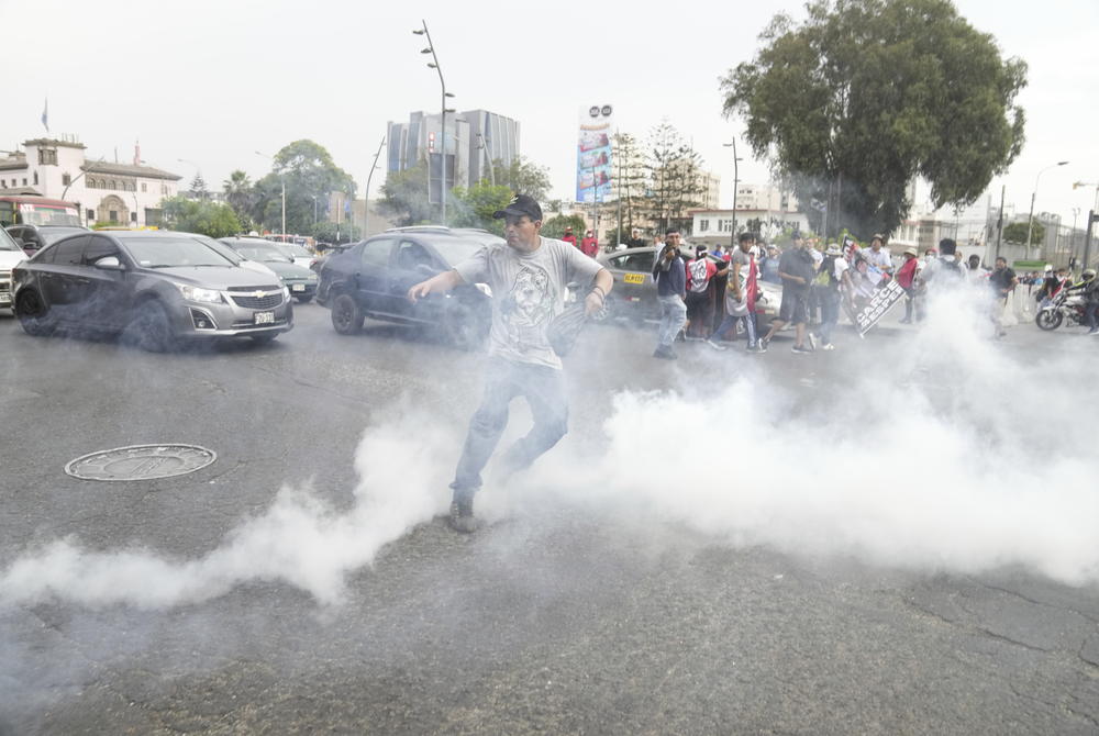 An anti-government protester throws a tear gas canister back at the police in Lima, Peru, on Wednesday.