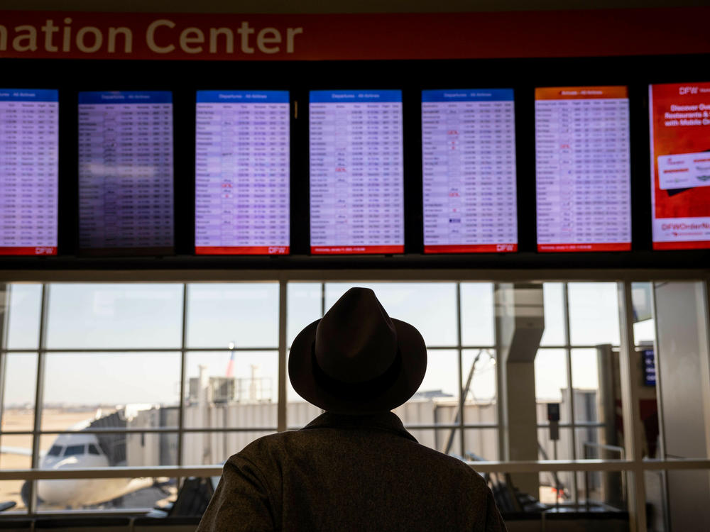 A passenger at Dallas-Fort Worth International Airport looks at a flight board after a system outage grounded thousands of flights throughout the country on Jan. 11.