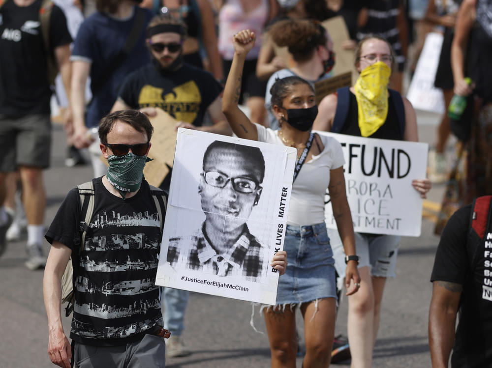 Demonstrators carry placards during a rally and march on June 27, 2020, over the death of Elijah McClain in Aurora, Colo.