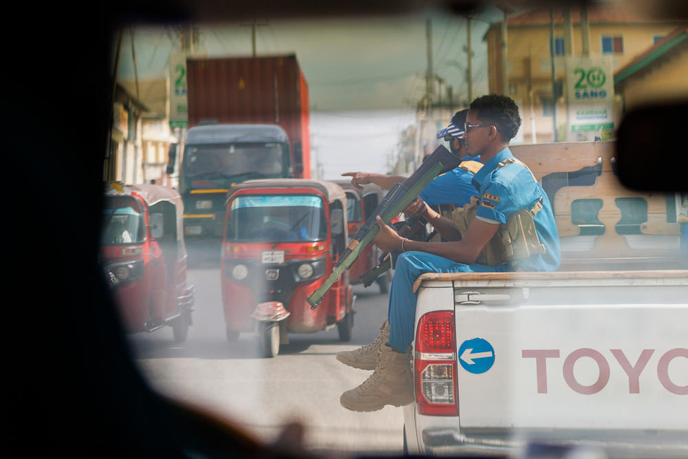 A private security team escorts an unmarked U.N. vehicle through the streets of Mogadishu. Aid workers, private business people, government officials and Western journalists regularly use bulletproof cars flanked by armed security details to move through the capital.